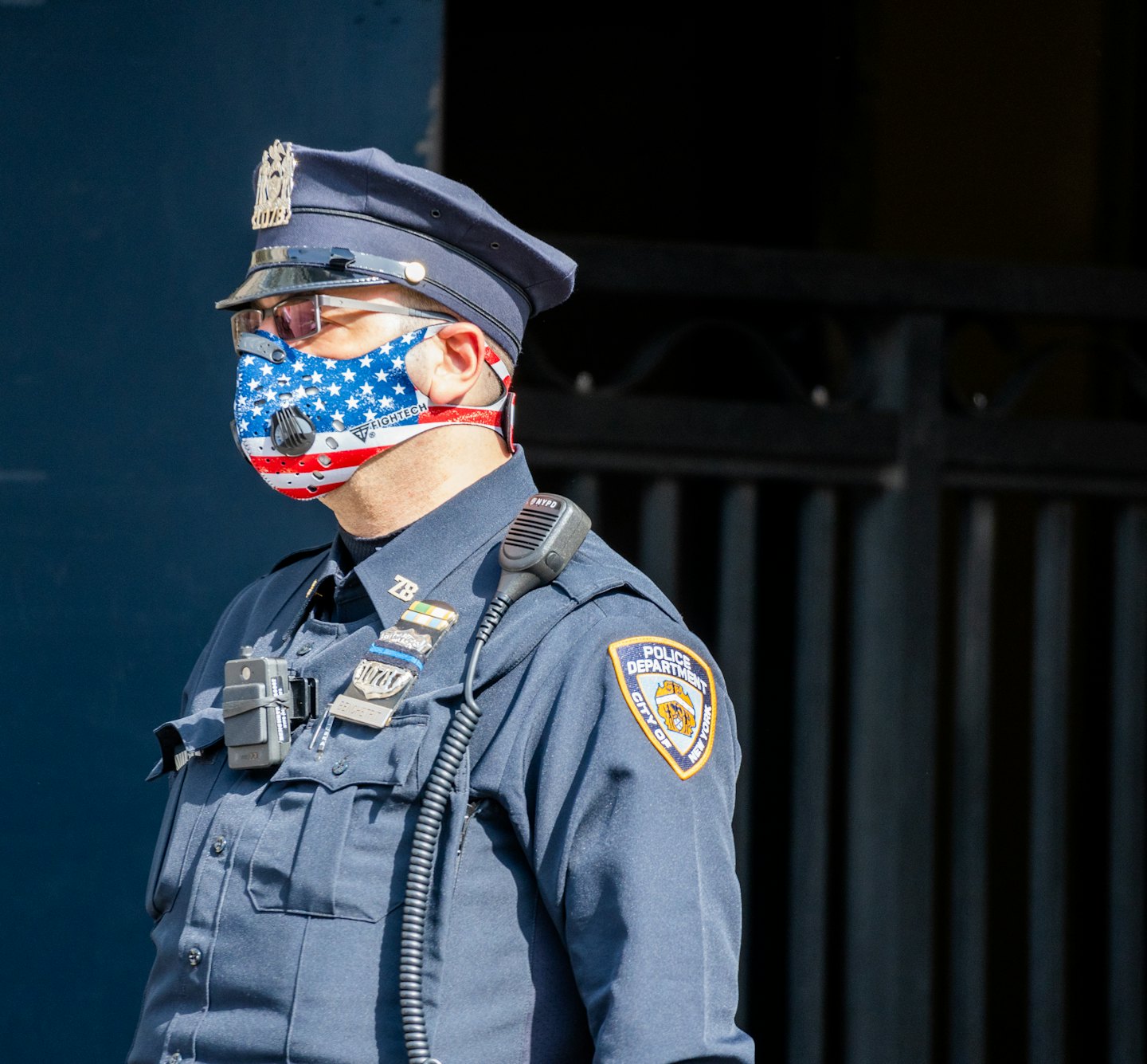 Police officer in uniform and American flag mask outdoors.