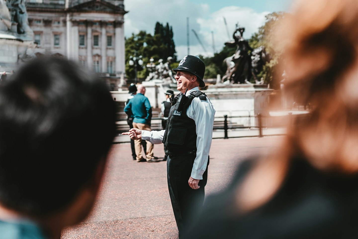Police officer in uniform laughs and points in a public square.